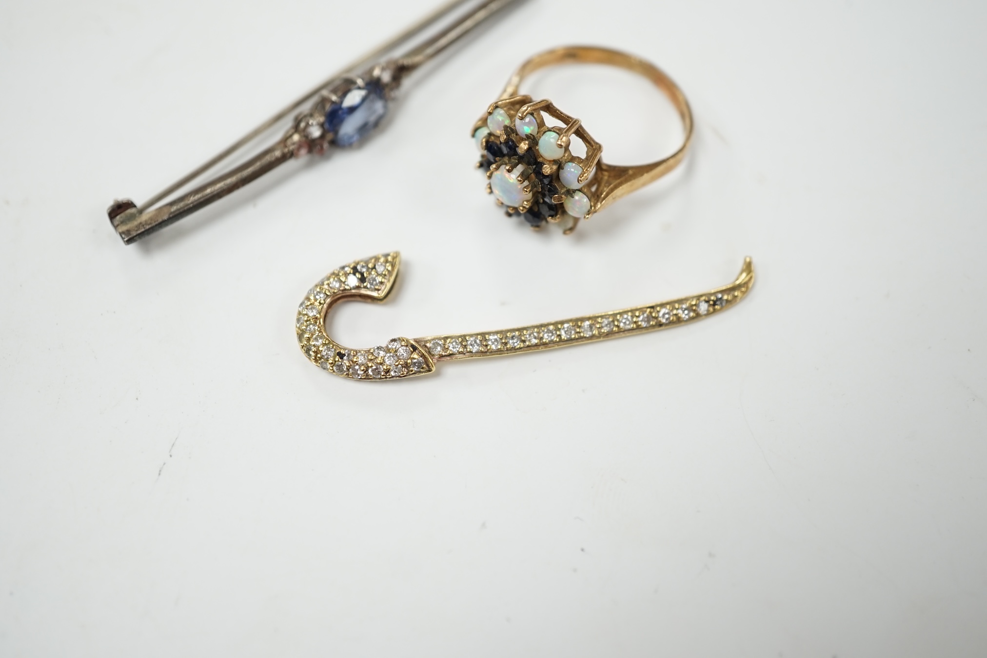 A yellow metal and pave set diamond miniature walking cane, 43mm, together with a 9ct gold, white opal and sapphire cluster set ring and a two colour sapphire set white metal bar brooch. Condition - poor to fair